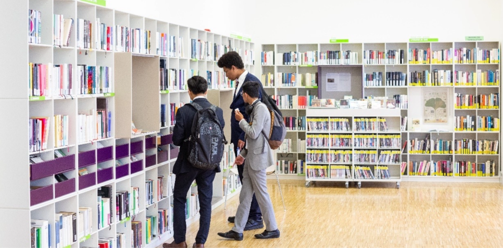 three students browsing through shelves of textbooks