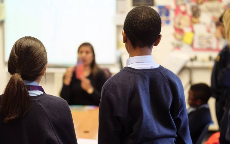 Two children in a classroom listening to their teacher